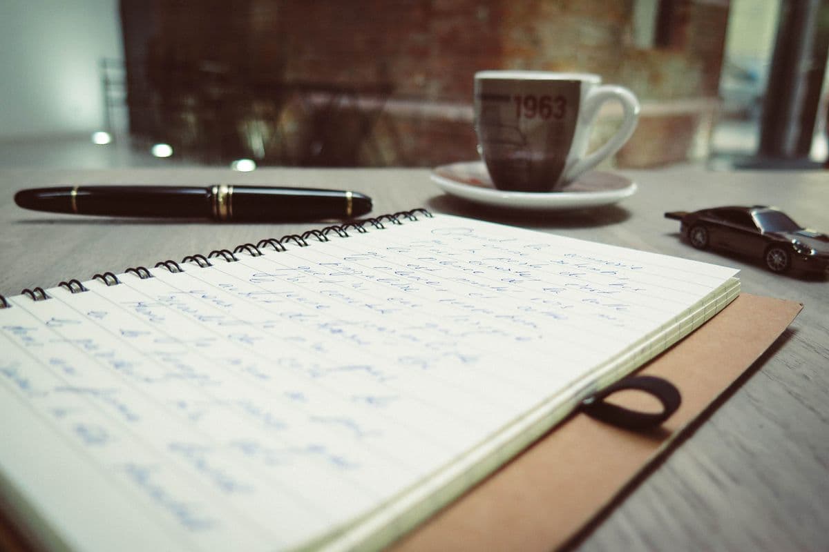 A notebook and coffee on a writing desk